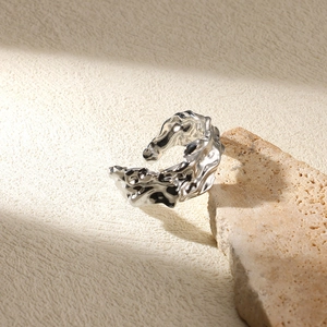Macro view of silver lava-style ring with fluid metal texture on travertine stone