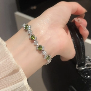 Close-up of elegant silver bracelet featuring oval green gemstones and zircon accents
