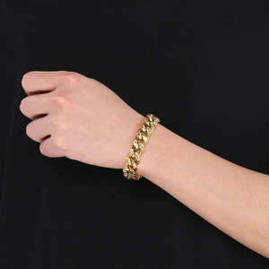 Close-up of a chunky hammered gold Cuban chain bracelet on a male wrist