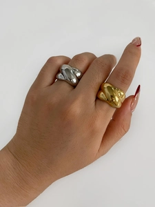 Macro detail of chunky twisted knot rings in gold and silver finish on a female hand