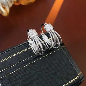 Détail de boucles d'oreilles multicouches argentées serties de zircons et design tressé