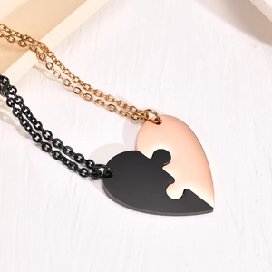 Macro detail of interlocking heart pendant necklaces in black and rose gold finishes