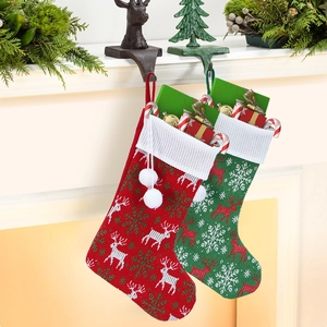 Festive red and green knitted Christmas stockings with reindeer patterns on fireplace