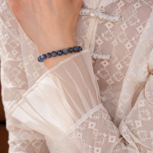 Detail of blue kyanite beaded bracelet on wrist with elegant lace clothing background