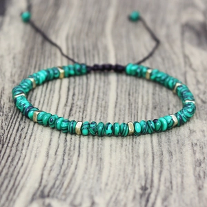 Close-up of green striped beads and gold metal spacers on adjustable braided bracelet