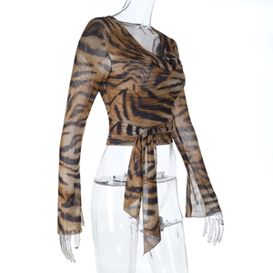 Dettaglio del crop top trasparente con stampa tigre, maniche lunghe e lacci in vita