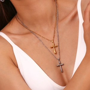 Detail of layered gold and silver cross pendants on Figaro chains worn by a model