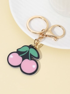 Detailed close-up of a pink cherry keychain charm with green leaves and gold metal chain