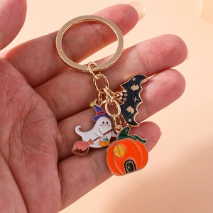 Halloween keychain with cartoon ghost, pumpkin, and bat charms held by hand
