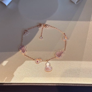 Detail of rose gold bracelet with pink shell wulu pendants and a red gemstone inlay