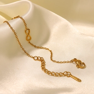 Gold stainless steel infinity symbol bracelet with adjustable chain on white satin