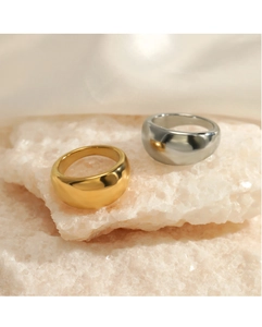 Polished gold and silver dome rings displayed on a textured stone base for women