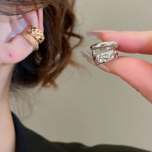 Detailed view of layered metallic ear cuff with textured finish in gold and silver