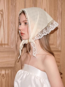 Close-up of cream white lace headscarf with delicate floral embroidery and cutouts