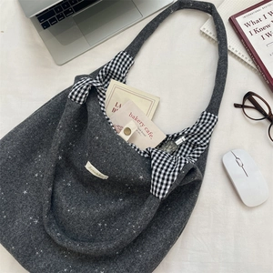 Borsa tote grigio scuro con motivo a stelle e fodera scozzese su scrivania bianca