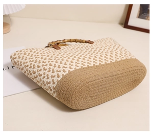 Detail of woven tote bag featuring a contrast bicolor pattern and natural bamboo handles