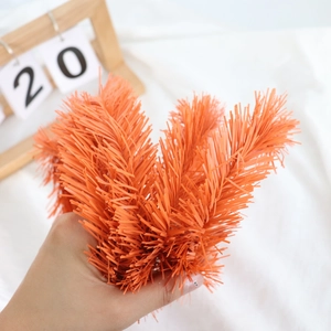 Close-up of fluffy orange PVC pine needle garland for festive home wall decoration