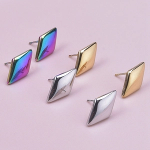 Close-up of geometric diamond-shaped steel earrings in rainbow, silver, and gold finishes