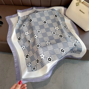 Detailed pattern of a square floral silk scarf with purple borders and a white handbag