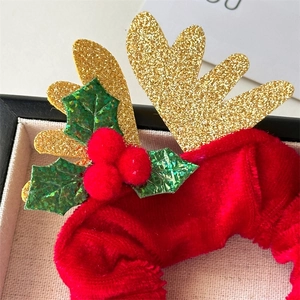 Détail d'un chouchou de Noël en velours rouge avec bois dorés et décor de houx