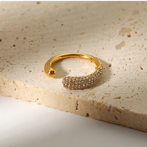 Macro shot of irregular gold ring with pave zircon stones on textured stone