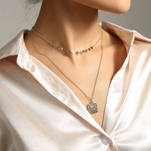 Close-up of double-layer necklace with crushed silver beads and square relief pendant
