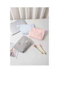Detailed view of checkered fabric cosmetic bags in light blue, pink, and gray colors