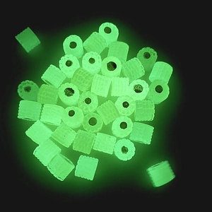 Luminous resin beads with corn texture glowing in bright neon green light on black background