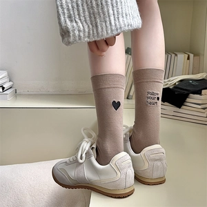 Close-up of khaki crew socks with black heart embroidery and Follow Your Heart text