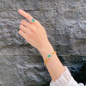 Macro detail of Italian vintage gold braided bracelet and emerald ring on model