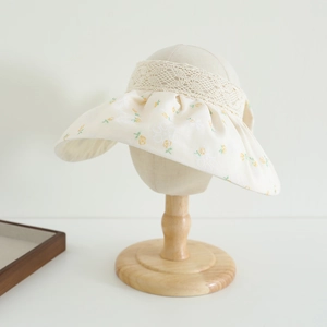 Detailed close-up of girls' sun hat featuring yellow floral patterns and lace trim