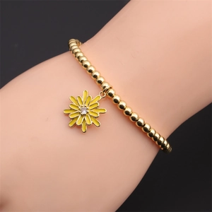 Gros plan d'un bracelet perlé doré avec breloque marguerite en émail jaune pour femme