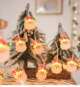 Close-up of Santa Claus LED string lights with warm glow on a mini Christmas tree