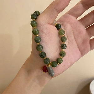 Detailed shot of green stone beads bracelet with gold spacers and hanging charms