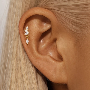 Close-up of golden marquise zirconia studs worn on the ear against blonde hair
