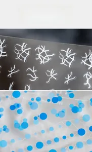 Macro detail of abstract white lines and blue polka dot patterns on nail art stickers