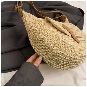 Detail view of beige woven straw bag with brown leather strap for summer beach vacation