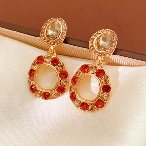 Close-up of vintage gold earrings with amber crystals on elegant white silk lining