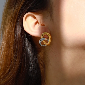 Detailaufnahme von zweifarbigen gold-silbernen Knotenohrringen an einem Model