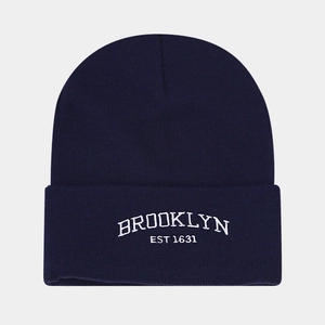 Macro detail of white Brooklyn embroidery on a dark blue knitted beanie hat