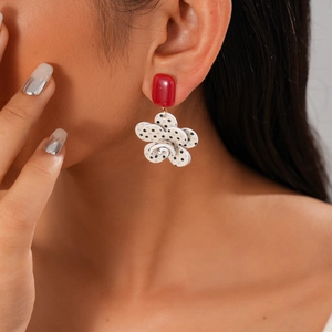 Close-up of red rectangular earring with layered white floral drop and black polka dots