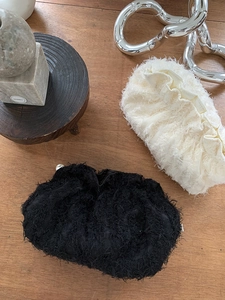 Détail de pochettes nuages moelleuses en noir et crème avec fermoirs perlés élégants
