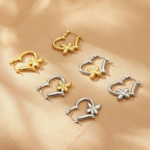 Detail of gold and silver heart butterfly earrings on elegant silk background