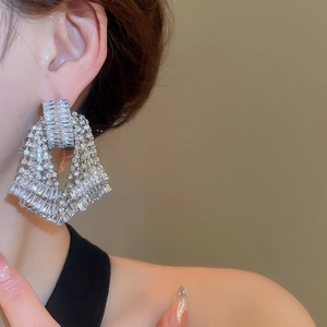 Detailed view of silver bow drop earrings with sparkling rhinestones worn on ear