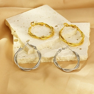Chic twisted gold and silver hoop earrings on elegant silk and stone display