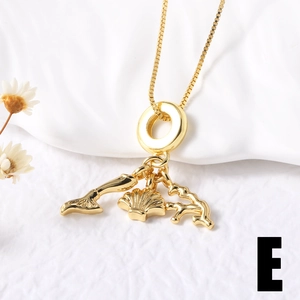 Detail of gold fish tail and shell pendant necklace on white fabric background