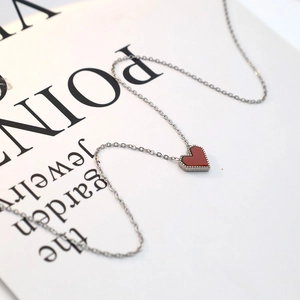 Macro shot of red heart necklace pendant with silver beaded edges and delicate thin chain