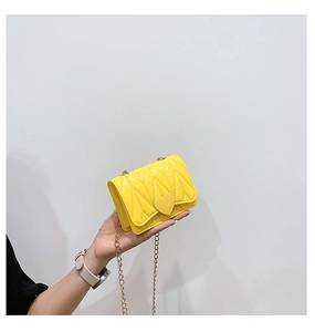Close-up of a yellow mini heart bag with V-shaped quilting and a gold chain strap