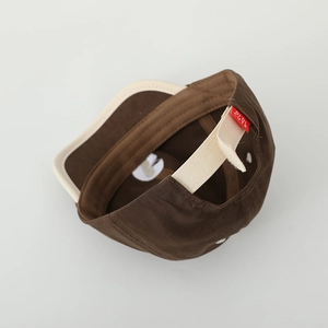 Close-up of brown cotton baseball cap with adjustable beige velcro strap and red tag