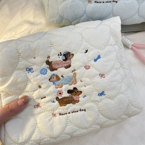 Detail van wit gewatteerd tasje met hartjespatroon en geborduurde puppy's en letters